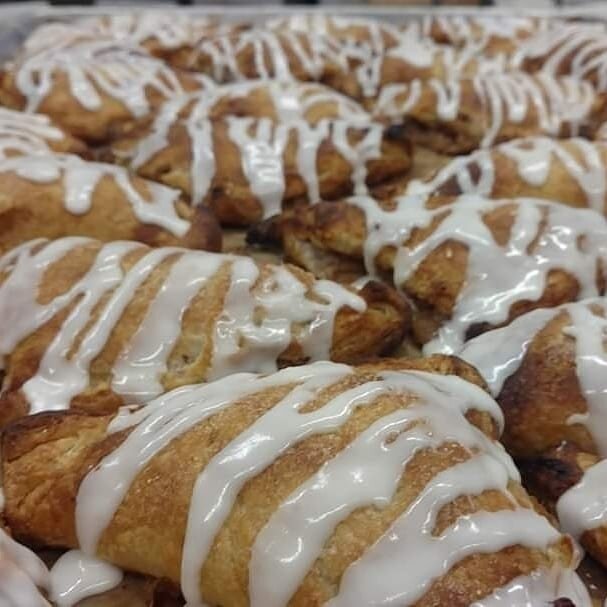 Freshly baked croissants drizzled with creamy icing, arranged in a tempting display. Perfect for breakfast or as a sweet treat.